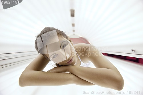 Image of Beautiful young woman tanning in solarium