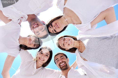 Image of Group of happy young people in circle at beach