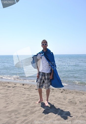 Image of funny superhero standing on beach