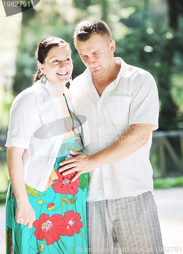 Image of Happy pregnant couple at beautiful sunny day in park