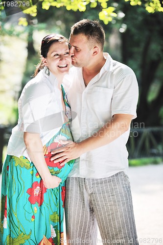 Image of Happy pregnant couple at beautiful sunny day in park