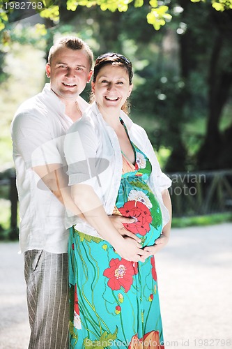 Image of Happy pregnant couple at beautiful sunny day in park