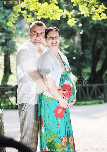 Image of Happy pregnant couple at beautiful sunny day in park