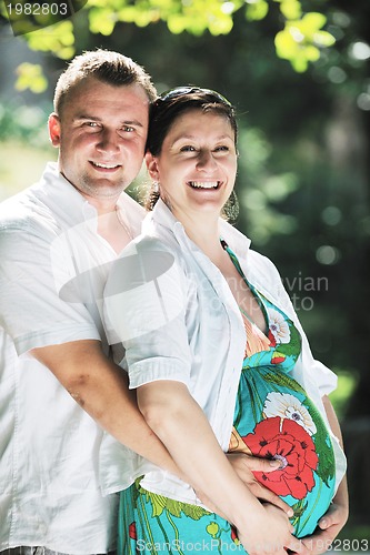 Image of Happy pregnant couple at beautiful sunny day in park