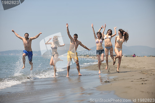 Image of happy people group have fun and running on beach
