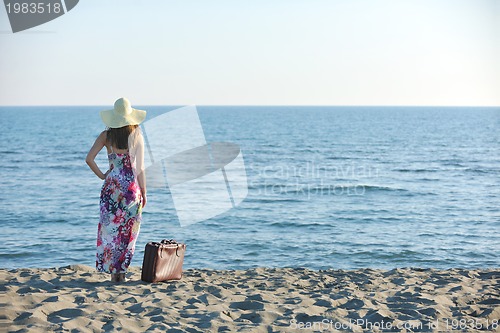 Image of woman with suitcase on the beach