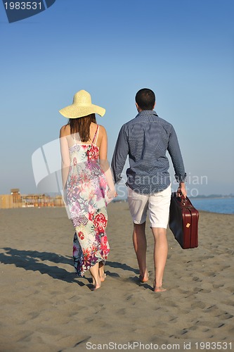 Image of couple on beach with travel bag