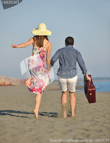 Image of couple on beach with travel bag