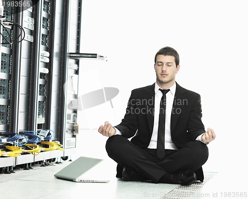 Image of businessman with laptop in network server room