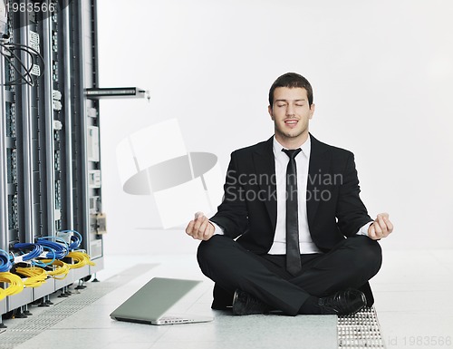 Image of businessman with laptop in network server room