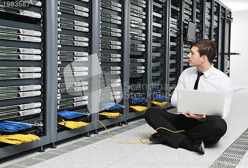 Image of businessman with laptop in network server room