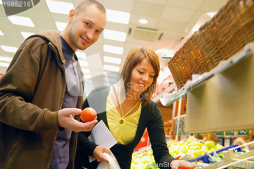 Image of happy couple buying fruits in hypermarket