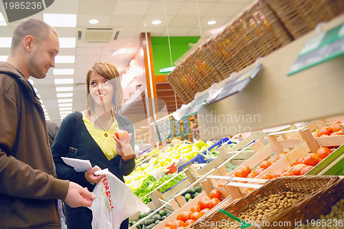 Image of happy couple buying fruits in hypermarket