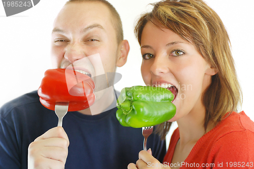 Image of happy couple with eating  peppers 