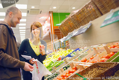 Image of happy couple buying fruits in hypermarket