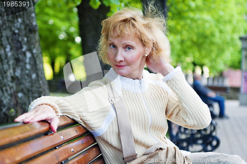 Image of a middle-aged woman sits on a park bench