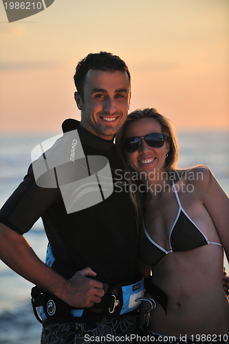 Image of surf couple posing at beach on sunset