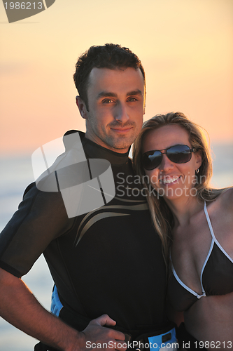 Image of surf couple posing at beach on sunset