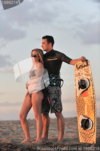 Image of surf couple posing at beach on sunset