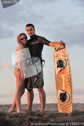 Image of surf couple posing at beach on sunset