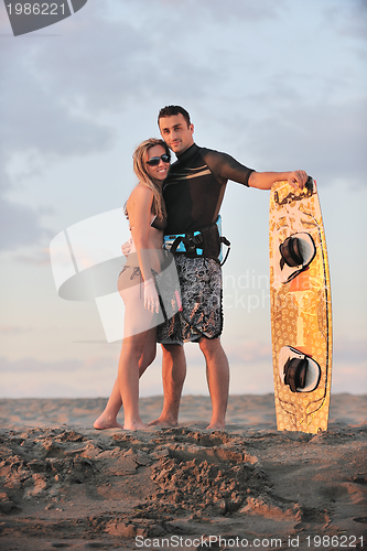 Image of surf couple posing at beach on sunset