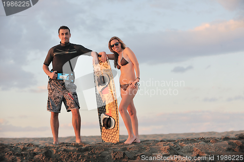 Image of surf couple posing at beach on sunset