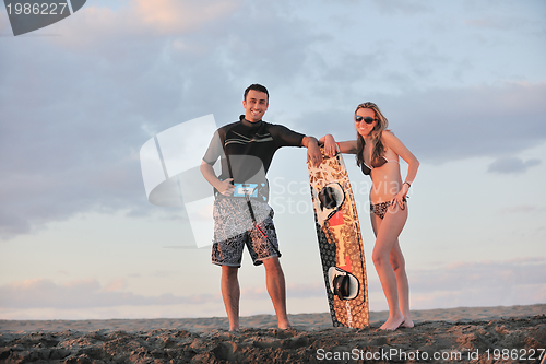 Image of surf couple posing at beach on sunset