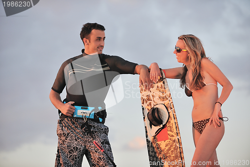 Image of surf couple posing at beach on sunset