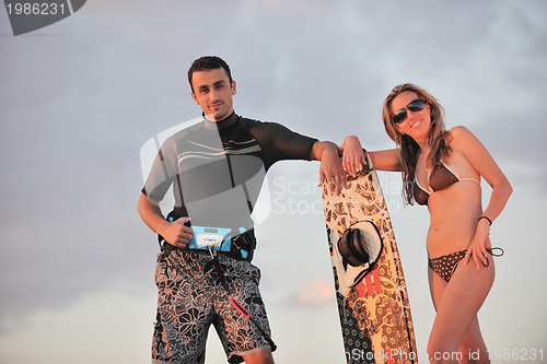 Image of surf couple posing at beach on sunset