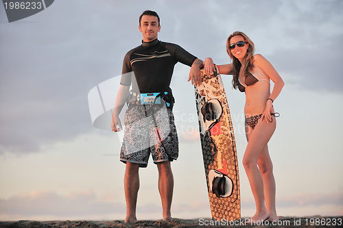 Image of surf couple posing at beach on sunset