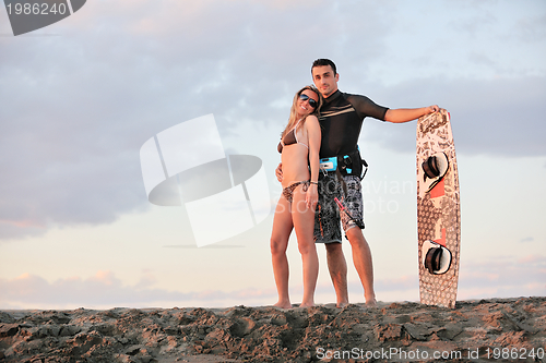 Image of surf couple posing at beach on sunset