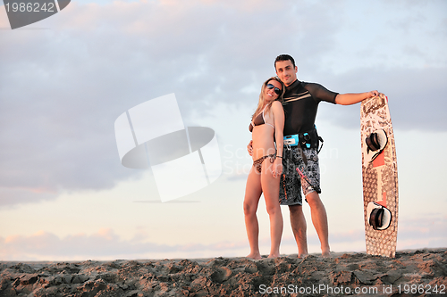 Image of surf couple posing at beach on sunset