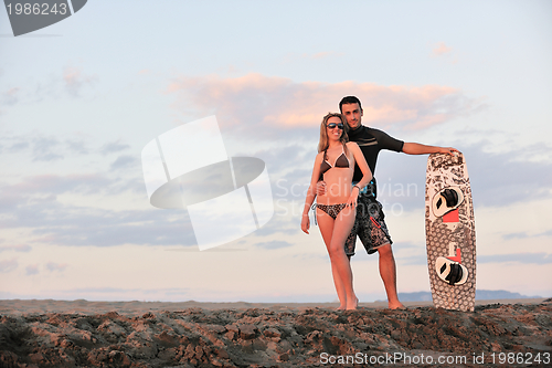 Image of surf couple posing at beach on sunset