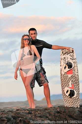 Image of surf couple posing at beach on sunset