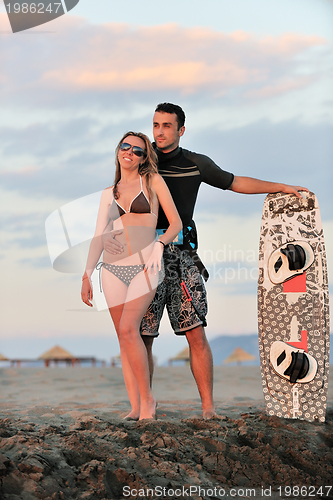 Image of surf couple posing at beach on sunset