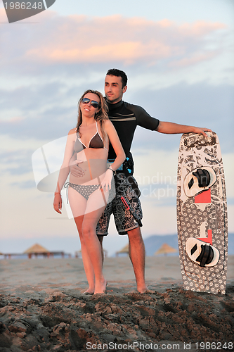 Image of surf couple posing at beach on sunset