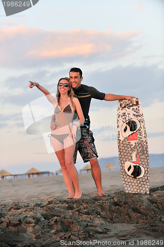 Image of surf couple posing at beach on sunset