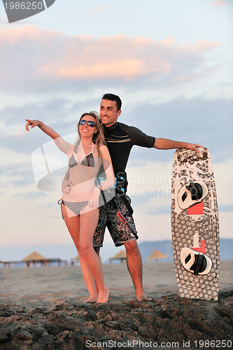 Image of surf couple posing at beach on sunset