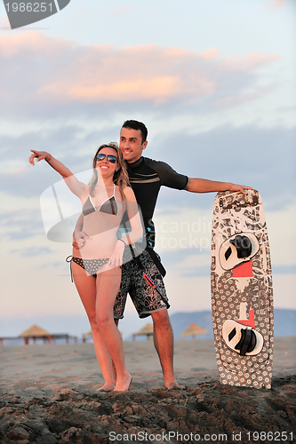 Image of surf couple posing at beach on sunset