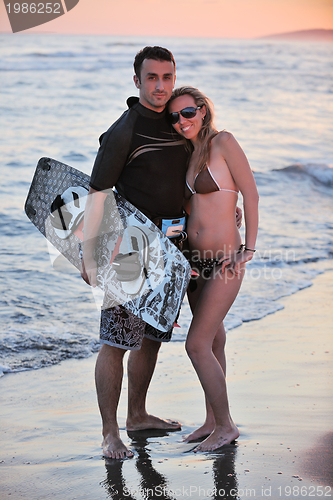 Image of surf couple posing at beach on sunset