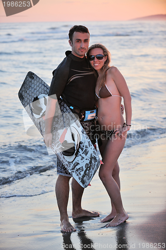 Image of surf couple posing at beach on sunset