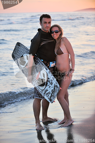 Image of surf couple posing at beach on sunset