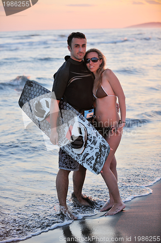 Image of surf couple posing at beach on sunset