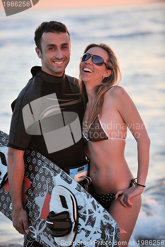 Image of surf couple posing at beach on sunset