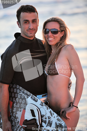 Image of surf couple posing at beach on sunset