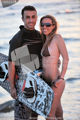 Image of surf couple posing at beach on sunset