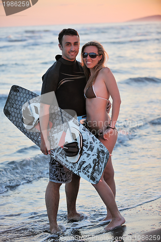 Image of surf couple posing at beach on sunset