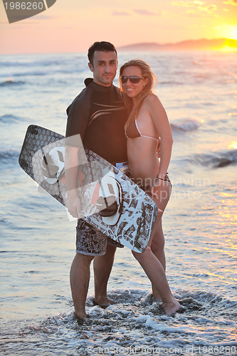 Image of surf couple posing at beach on sunset