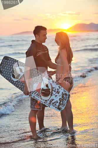 Image of surf couple posing at beach on sunset