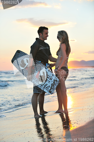 Image of surf couple posing at beach on sunset